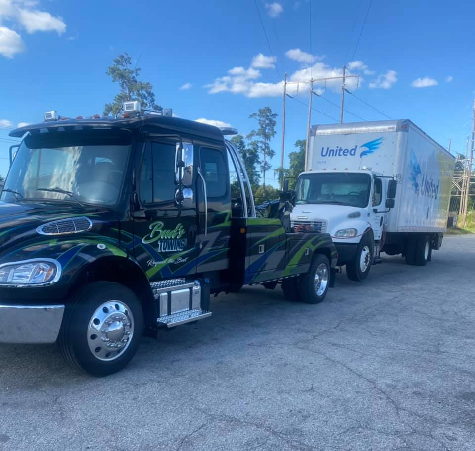 Buds Tow truck pulling a fleet truck behind